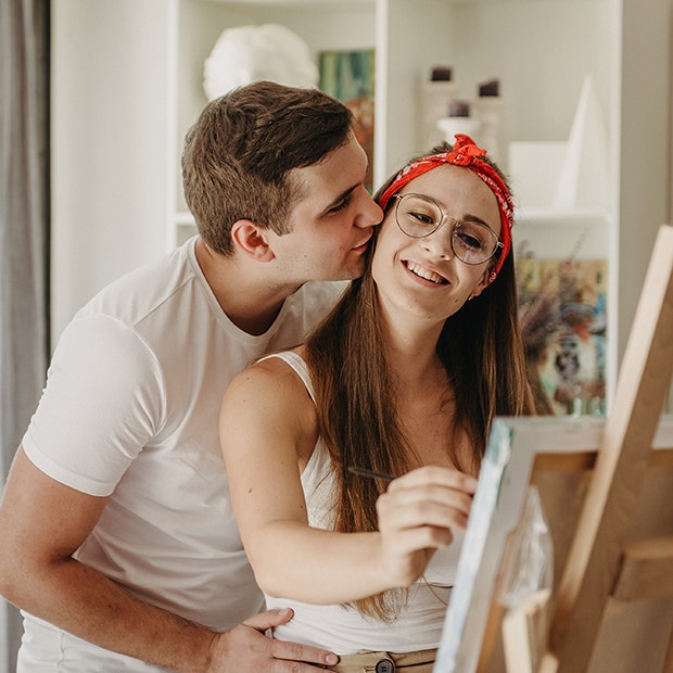 woman painting with man kissing her cheek