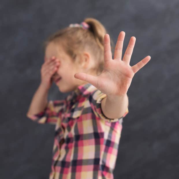 Little girl covering her eyes and gesturing &amp;quot;stop&amp;quot; with her hand. 