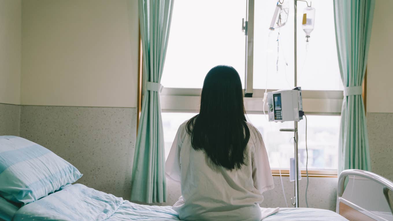 woman sitting on hospital bed looking out window