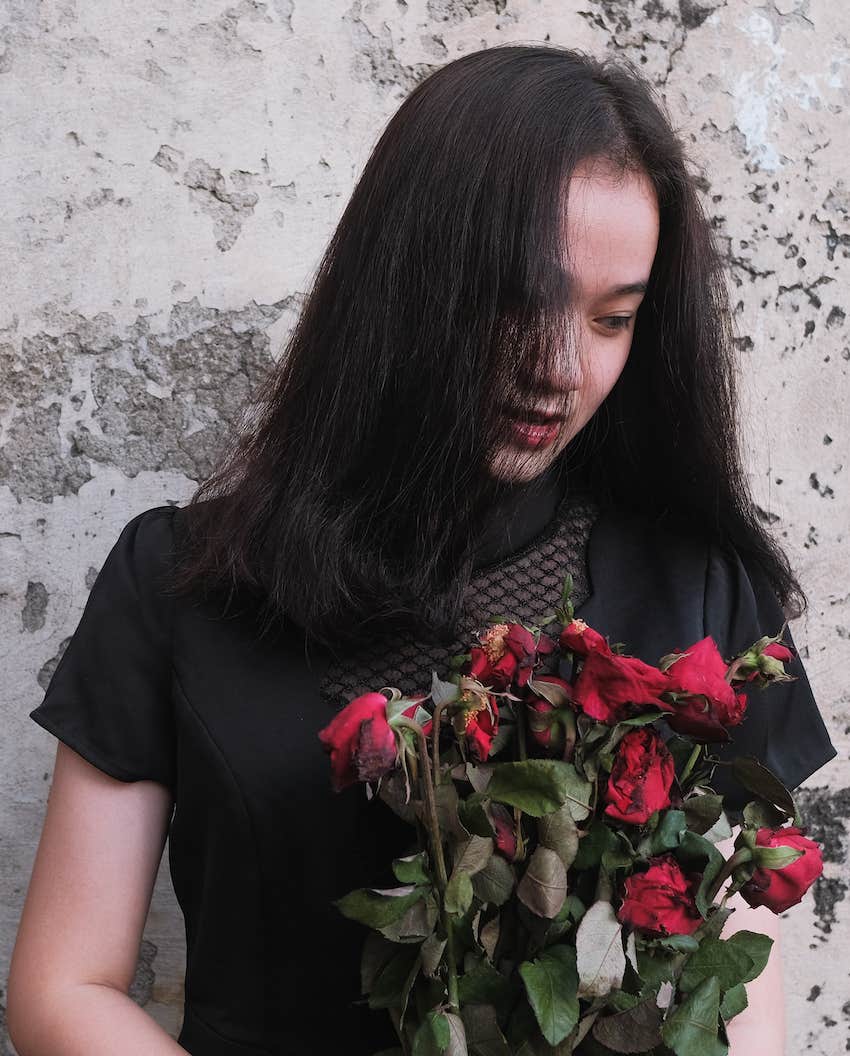 She holds the wilted roses from a husband who cheated
