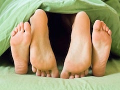 Feet at the foot of the bed under sheets