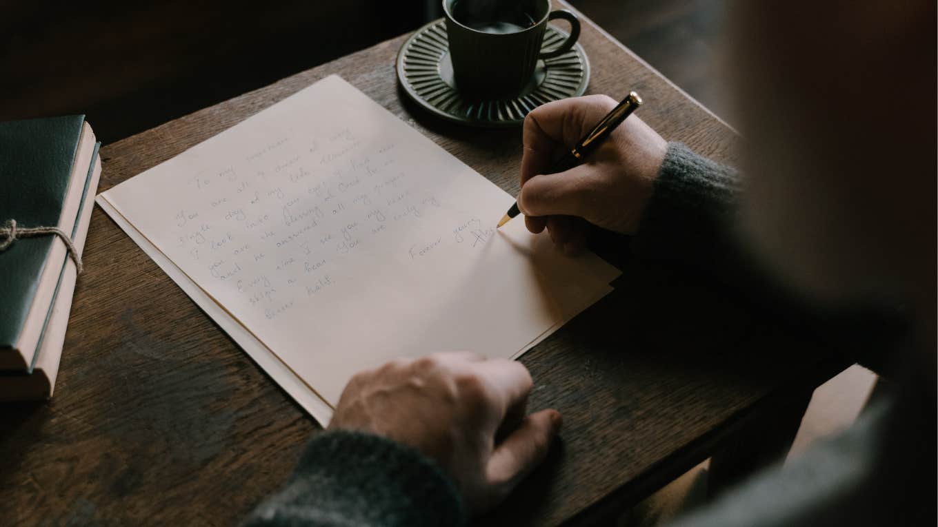 man writing letter at desk with coffee