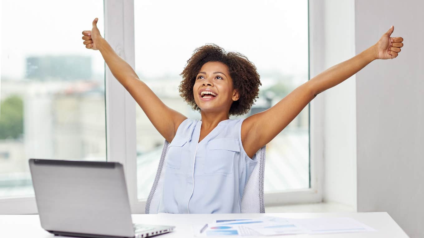 woman celebrating at work with arms raised