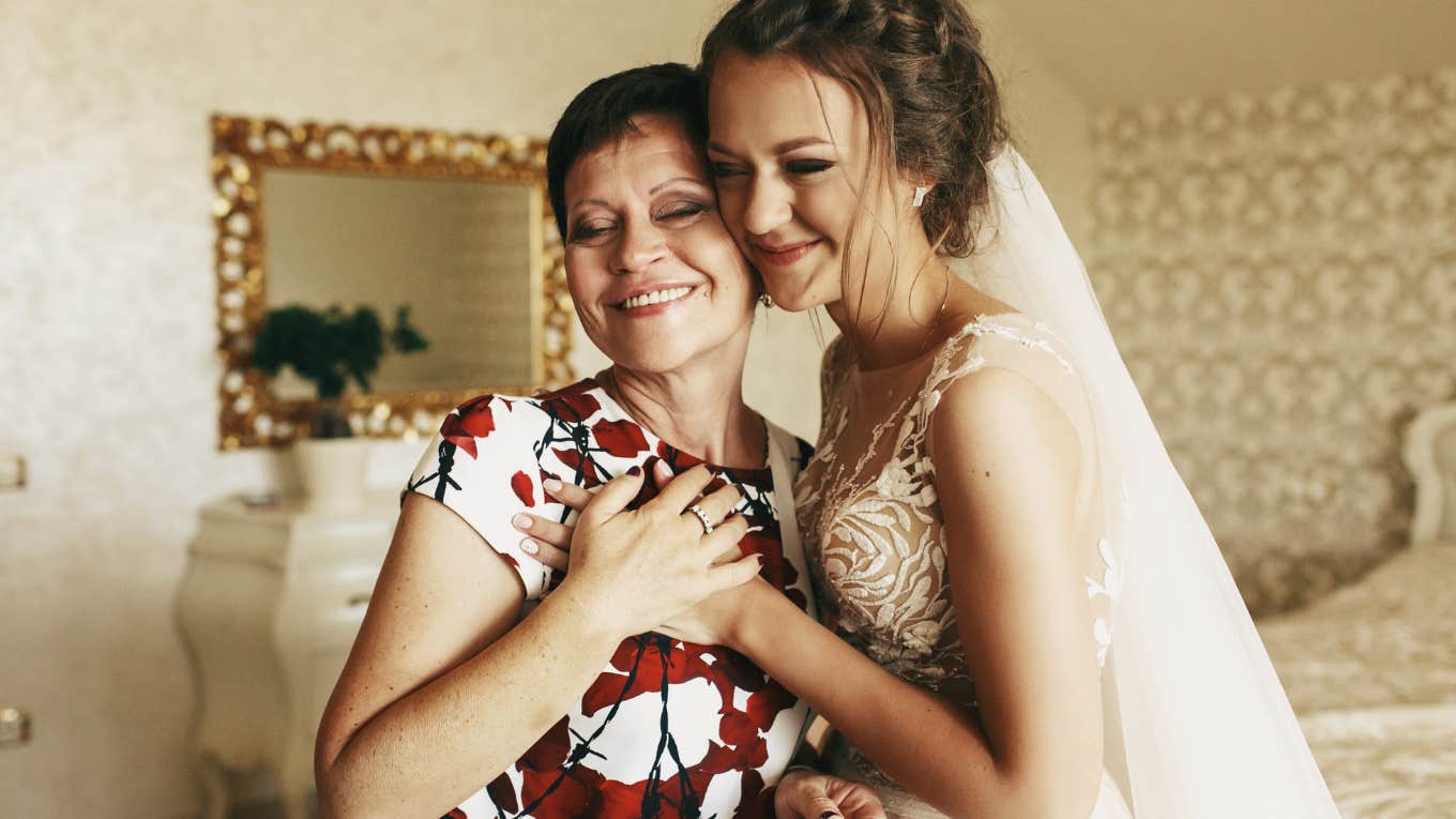 mother holds bride's hand standing with her in the room