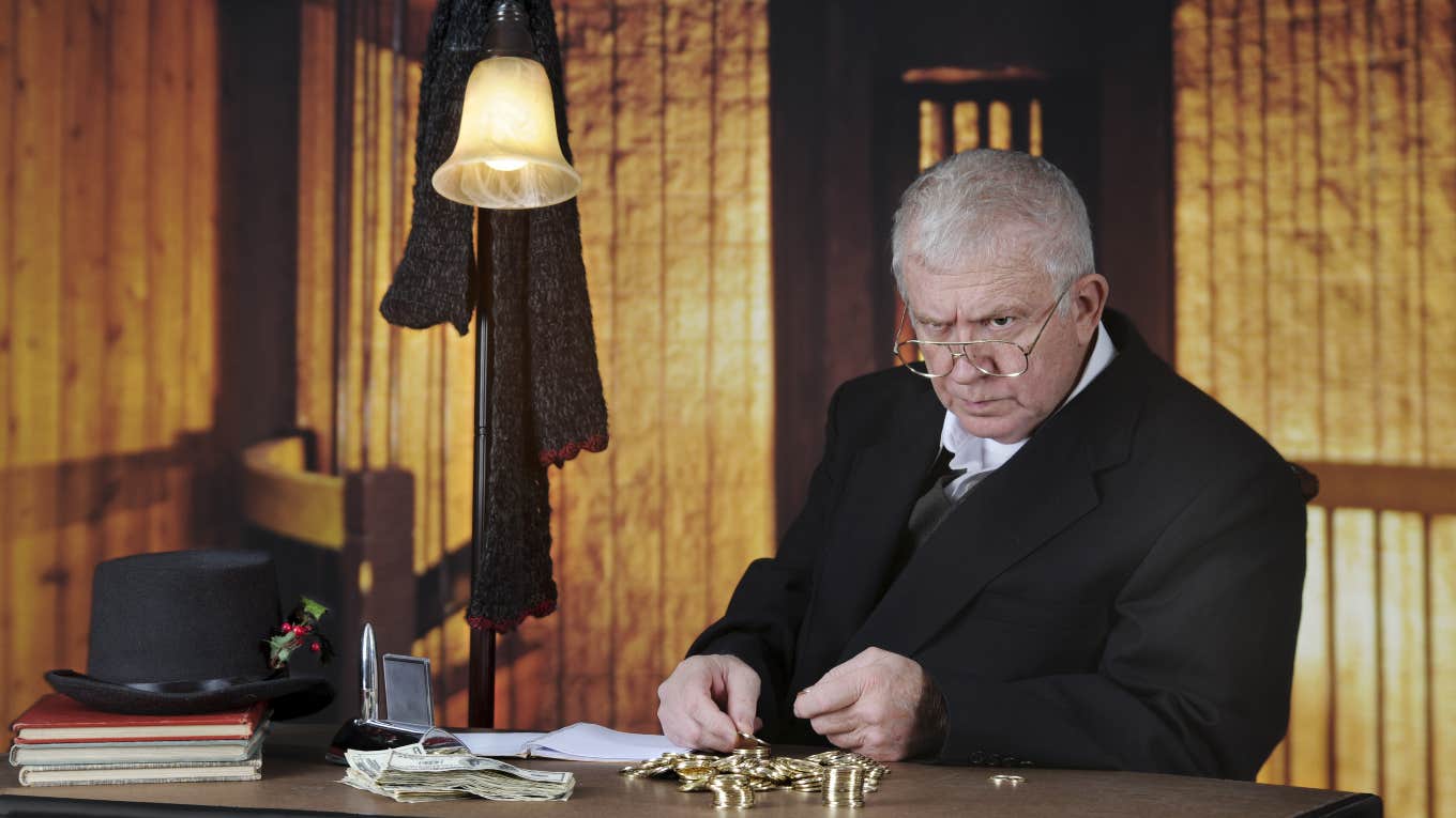 Scrooge counting coins at desk