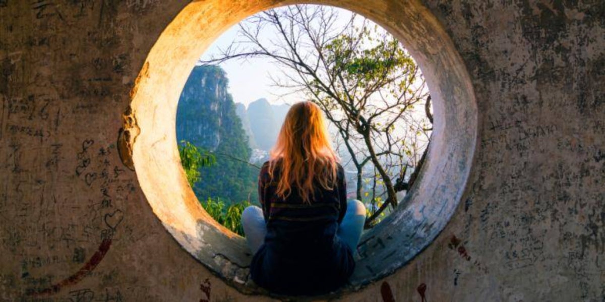 woman in tunnel facing away meditating