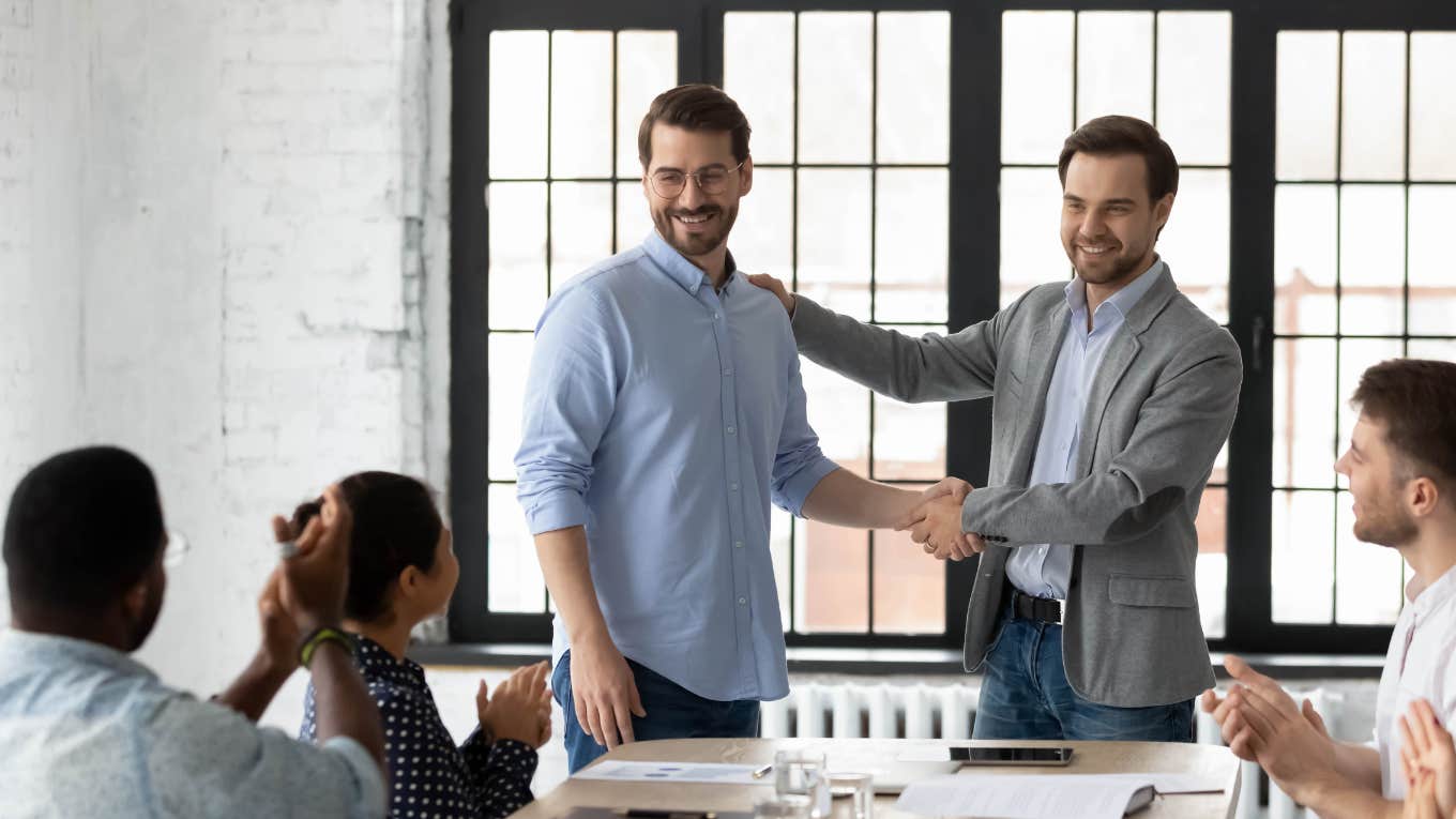 Proud boss encouraging and thanking happy employee for good job and shaking his hand
