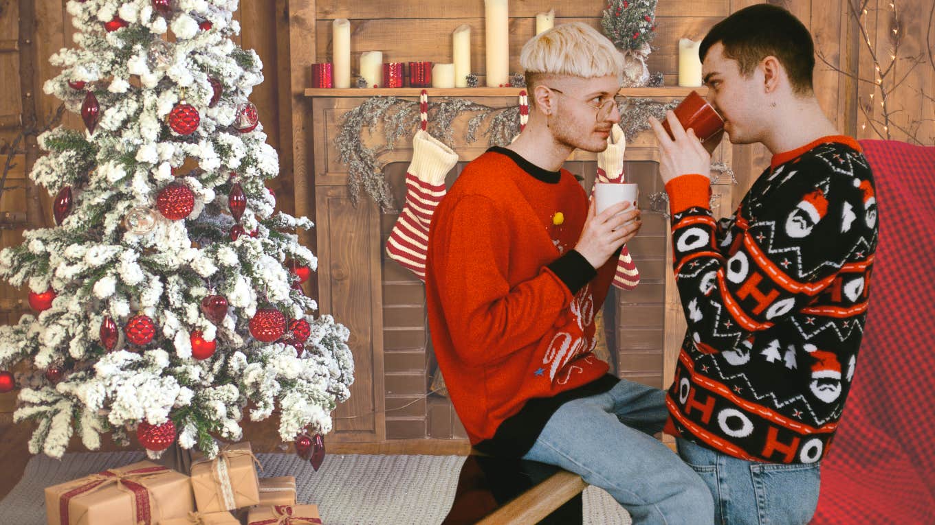 Two men drinking coffee and talking near a Christmas tree