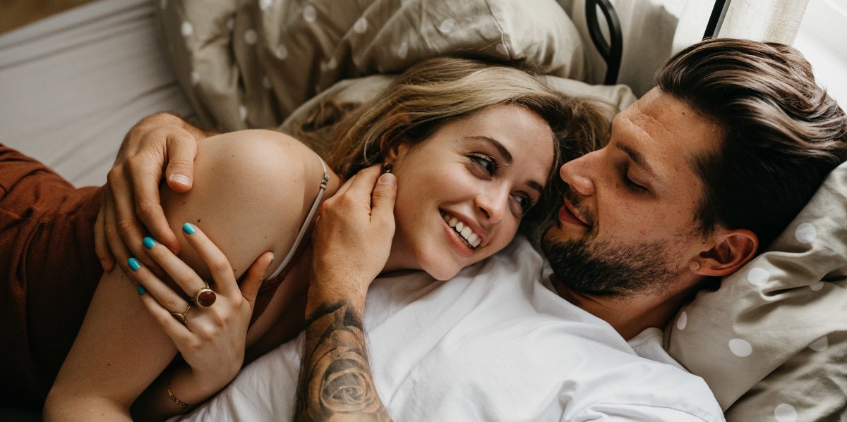 man and woman cuddling in bed