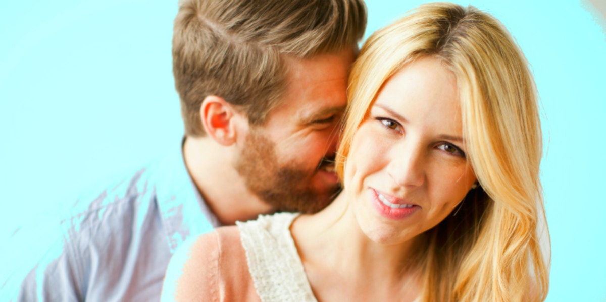 blonde couple against light blue background, he kisses her neck