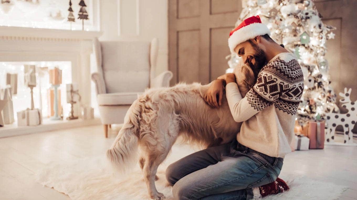 man in Santa hat hugging dog