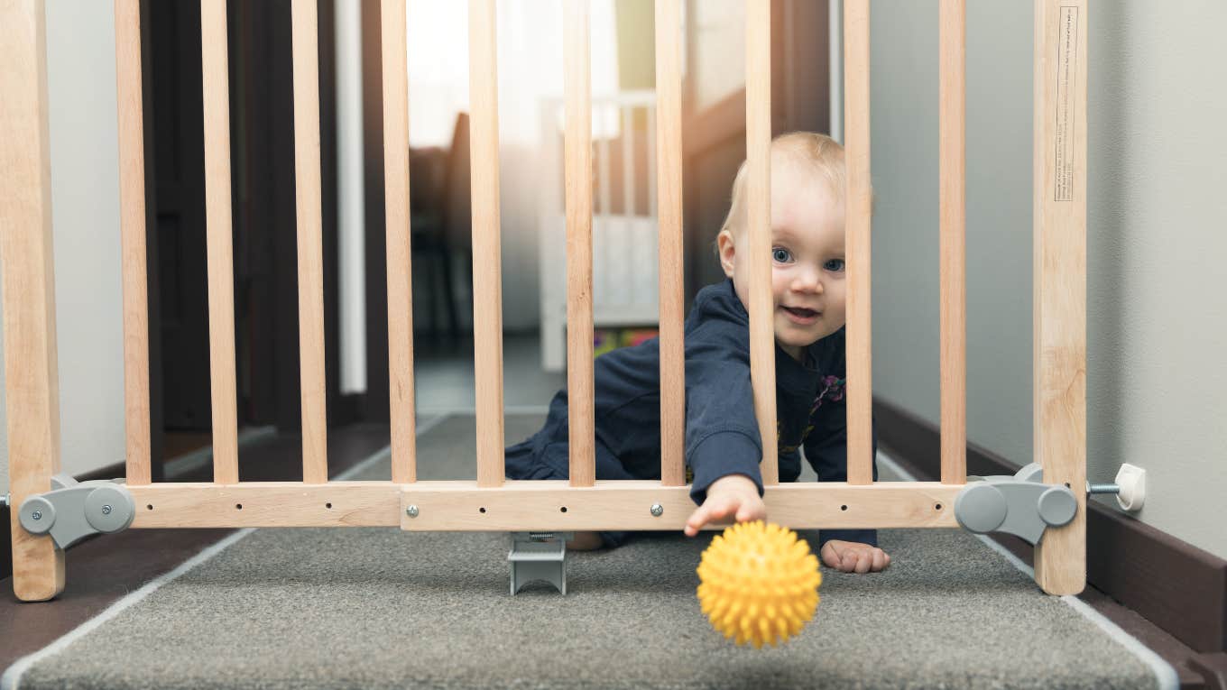 baby playing behind a baby gate