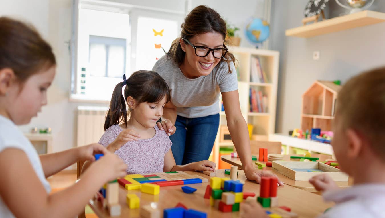 Preschool teacher with children playing with colorful wooden toys 