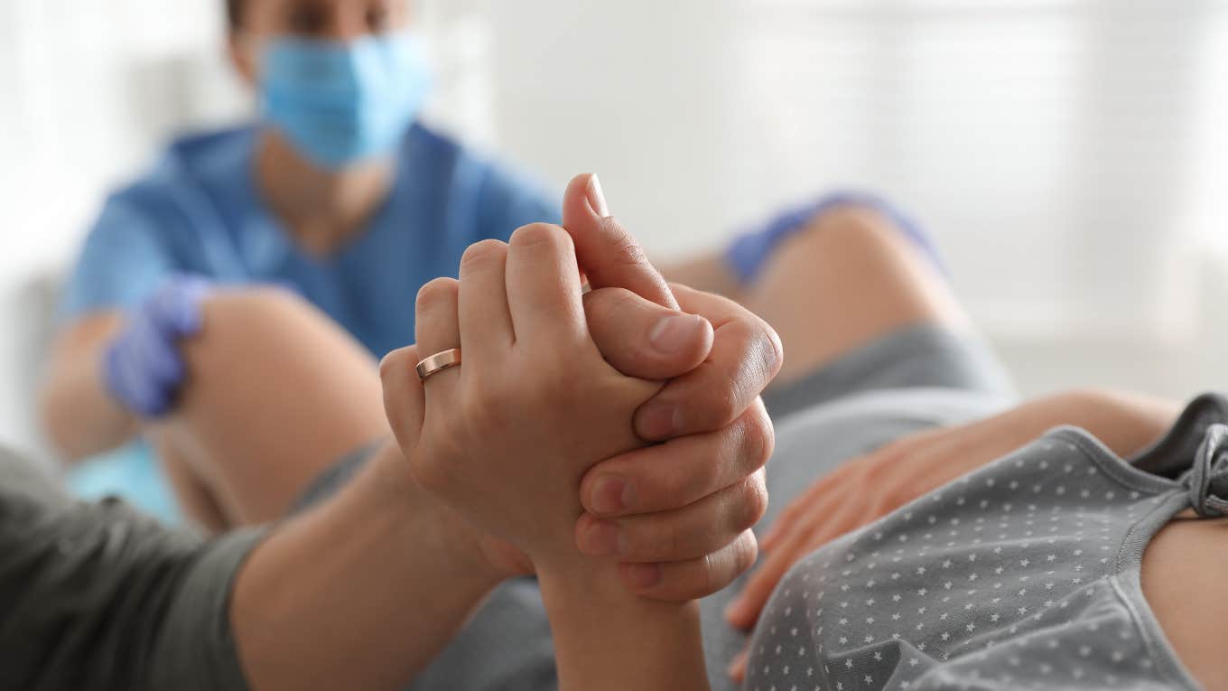 woman holding partner's hand while giving birth