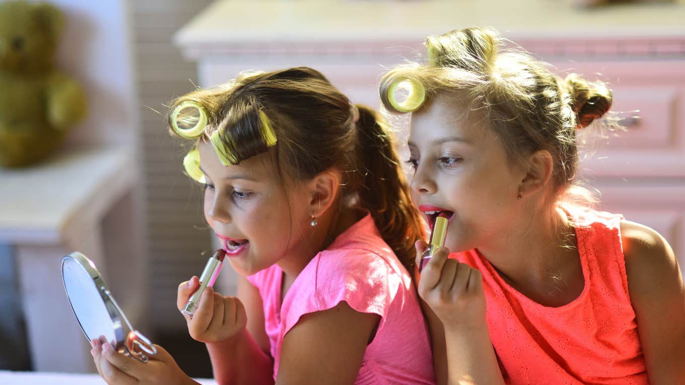 two girls putting lipstick on with curlers in their hair