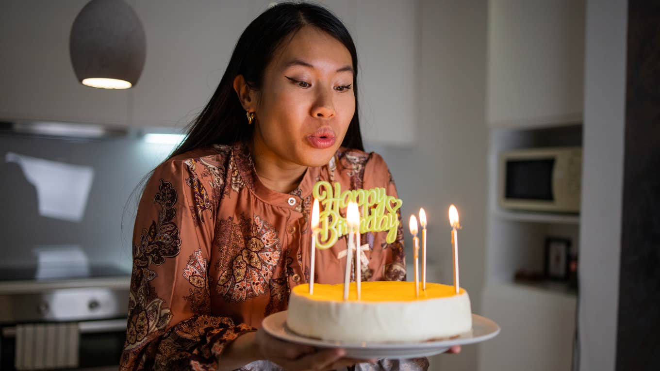 woman blowing out birthday candles on cake