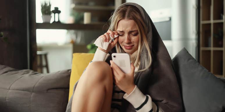 woman staring at phone while crying
