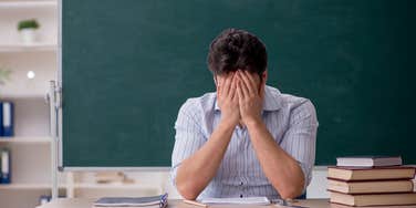 frustrated teacher with head in his hands