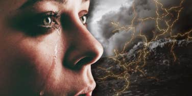 woman staring into a storm with a tear rolling down her cheek