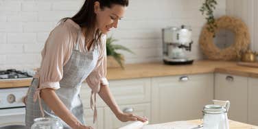 woman rolling out dough in kitchen
