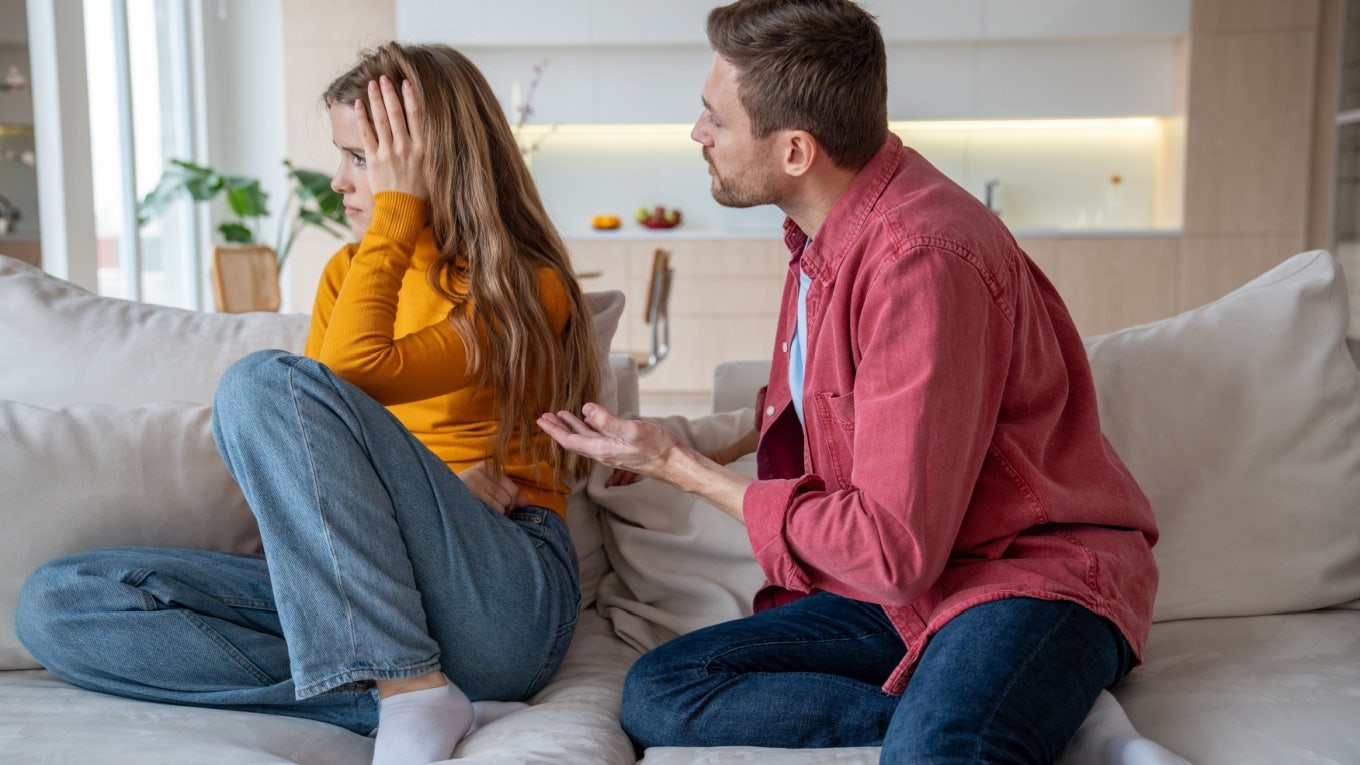 Couple arguing on couch and one partner not listening.