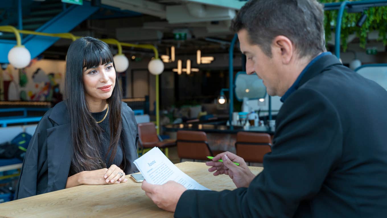 Human resource manager interviewing young applicant while looking at her resume