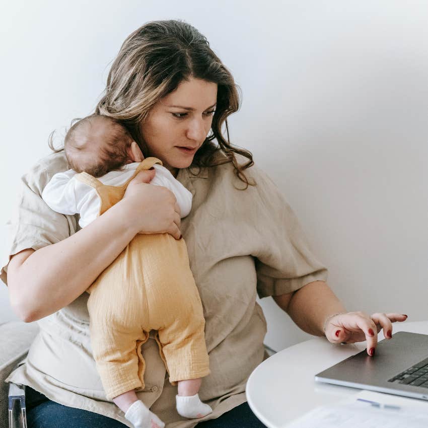 woman holding a baby working on computer