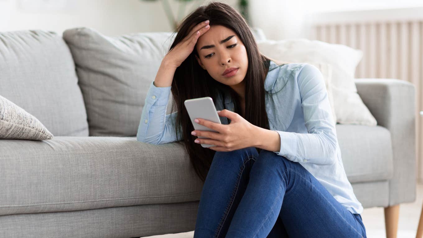 Teenage girl looking upset on her phone. 