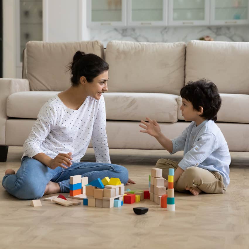 mother and little son building towers from toy construction bricks on floor together