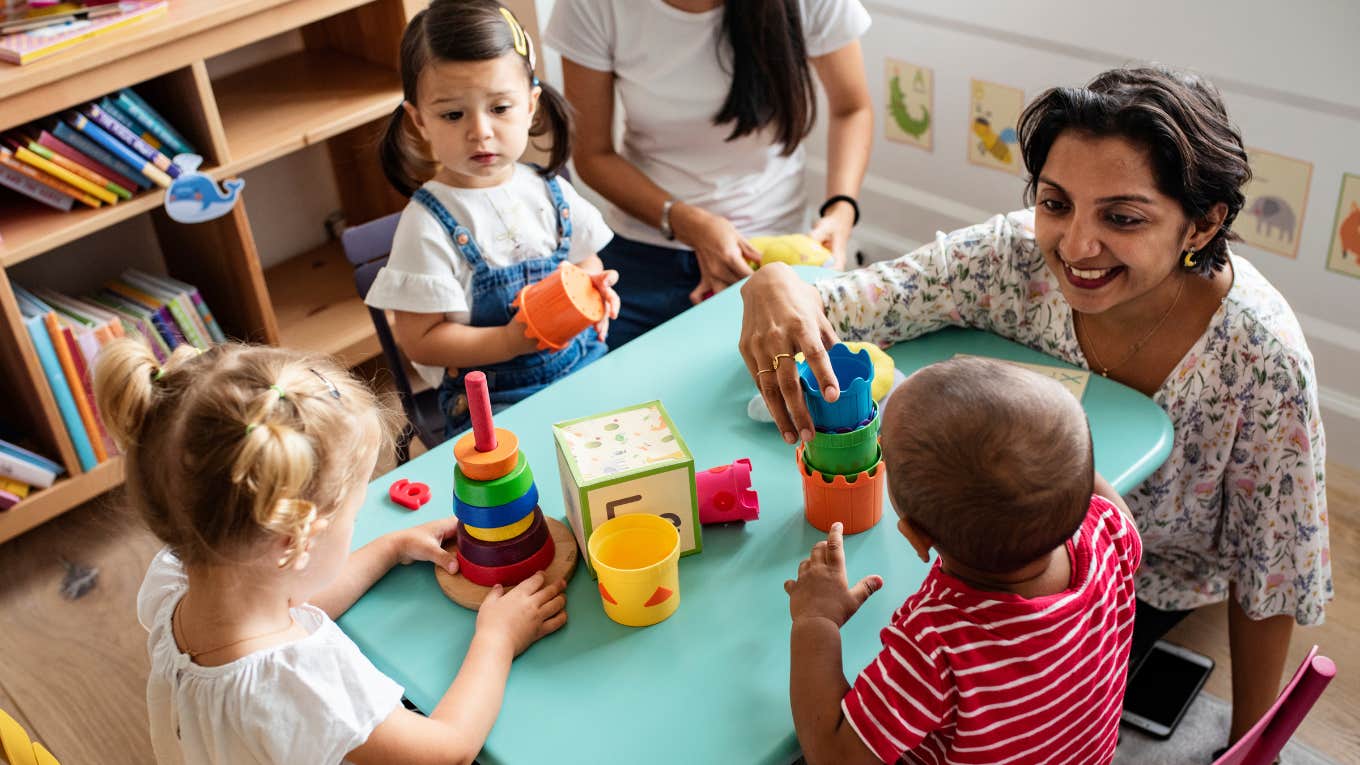 Nursery children playing with teacher in the classroom