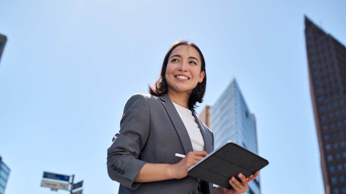 smiling business woman holding a tablet outside