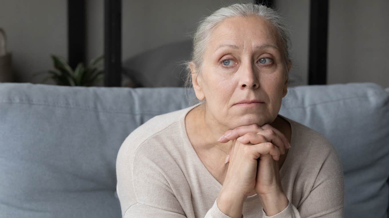 upset elderly woman sitting on couch