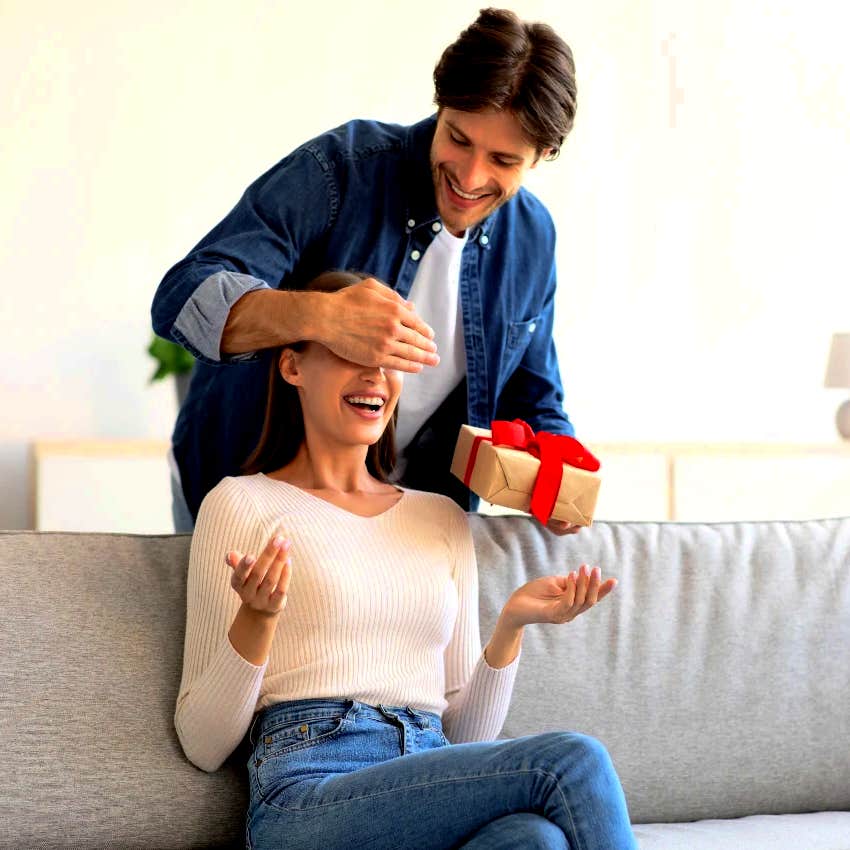 man covering woman's eyes giving her a present