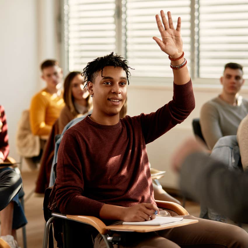 student raising his hand to ask a questing during a class at lecture hall.
