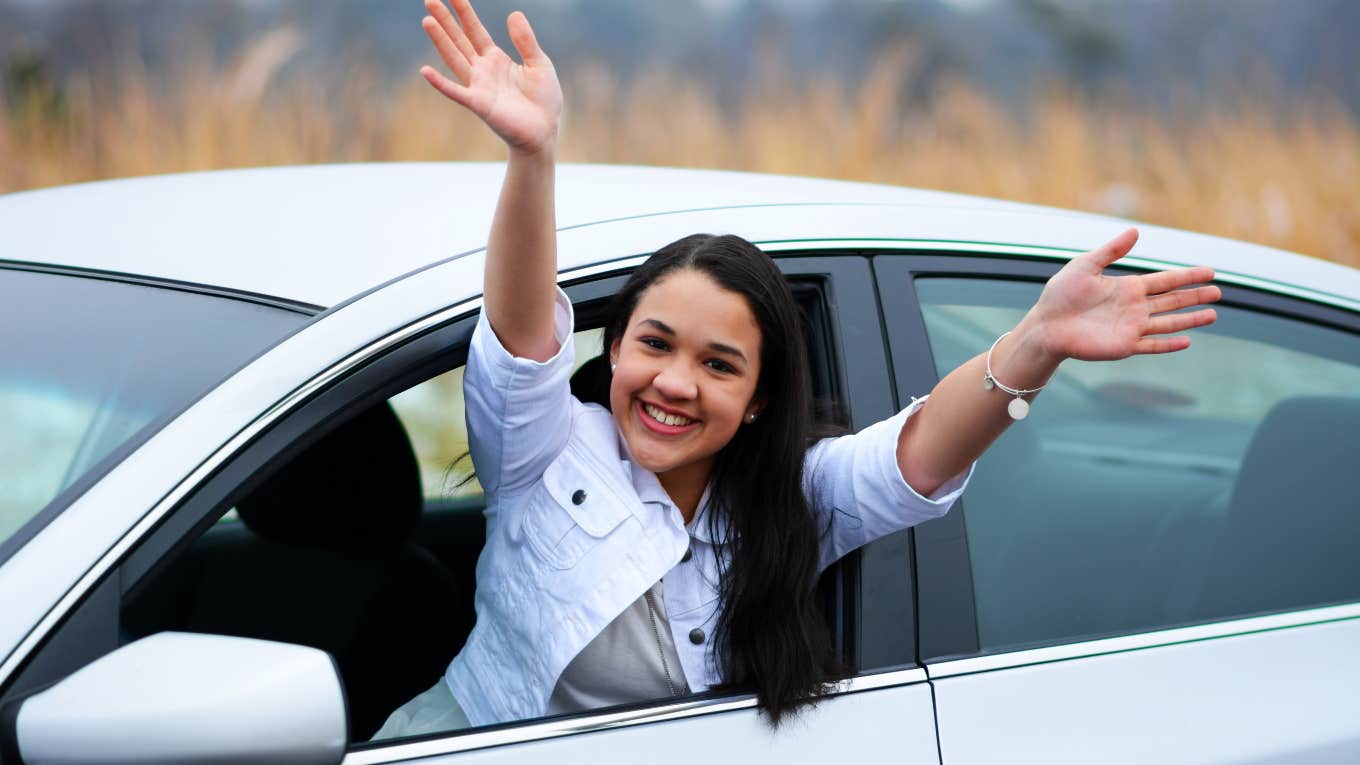 teen girl leaning excitedly out window of a car
