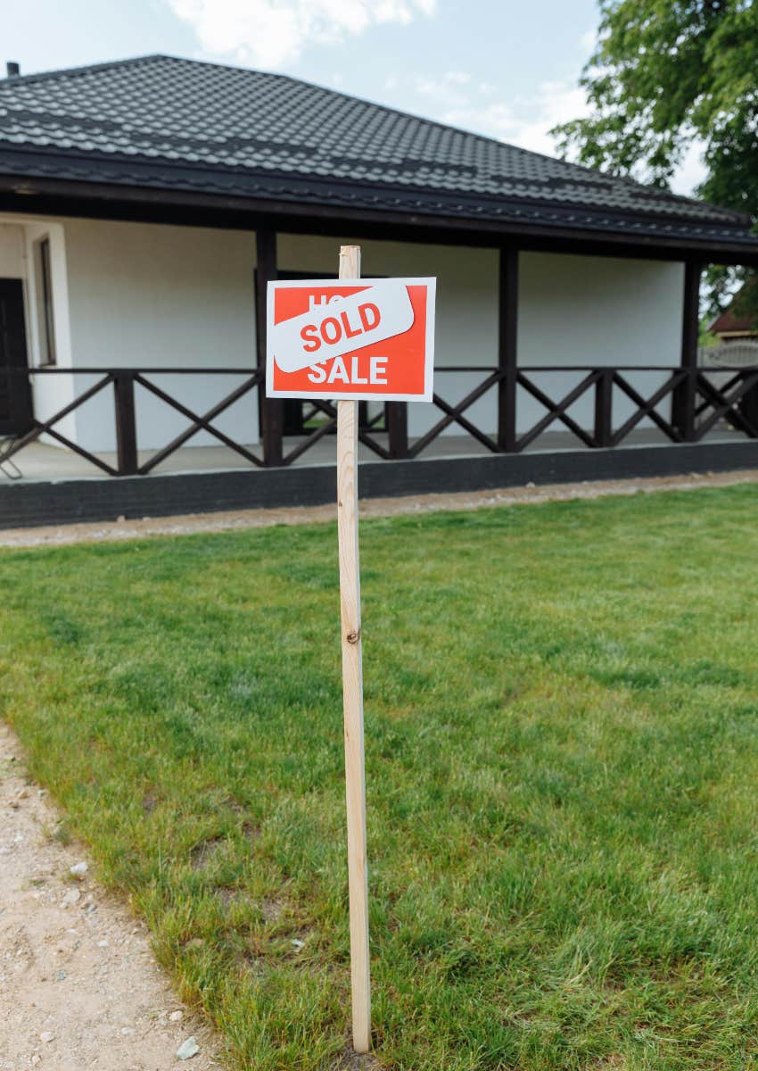 for sale sign covered by sold sign in yard of house