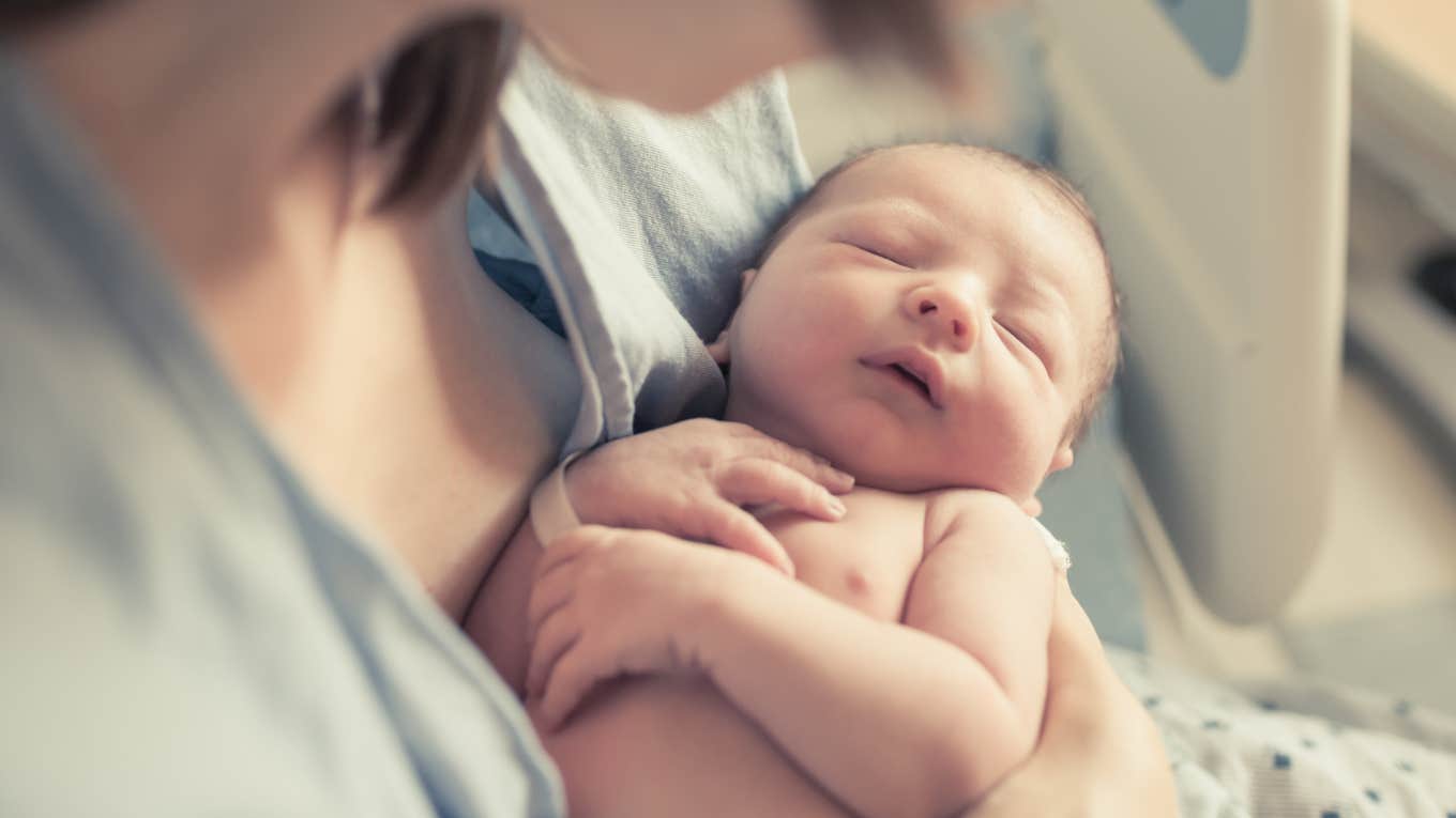 mom holding newborn baby in hospital bed