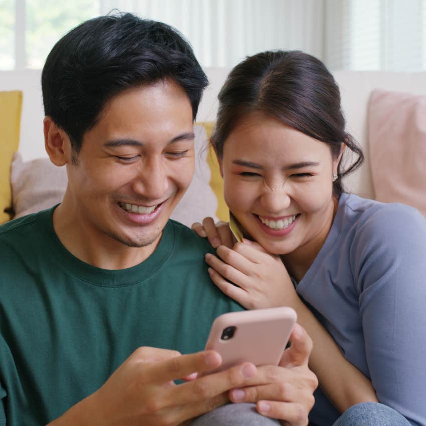 couple smiling while looking at phone together