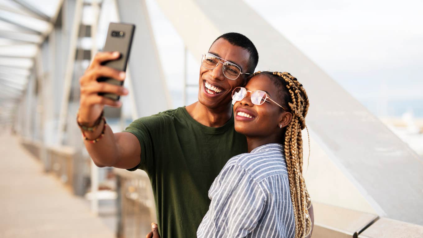 smilng couple taking selfie with phone outdoors