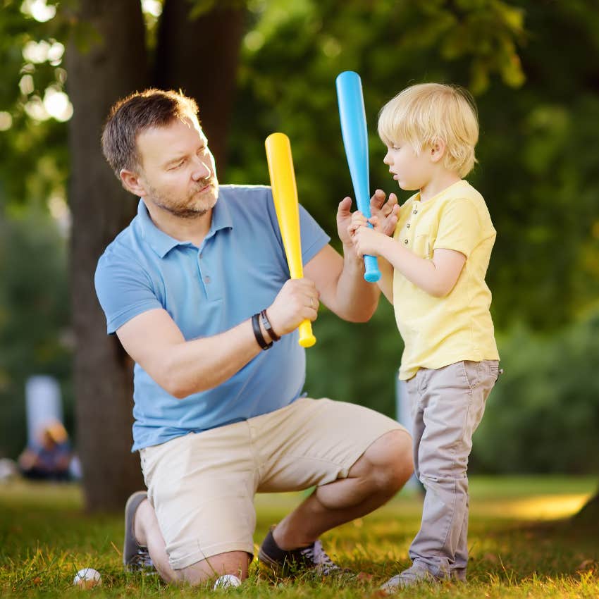 Dad and son playing with baseball bats in the yard. 