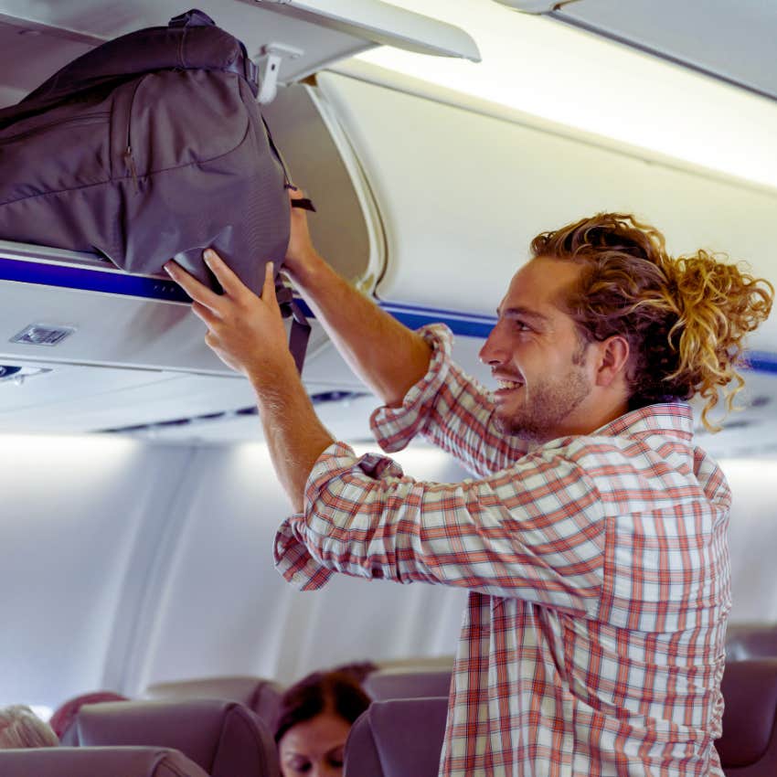 man putting luggage in plane's overhead bin