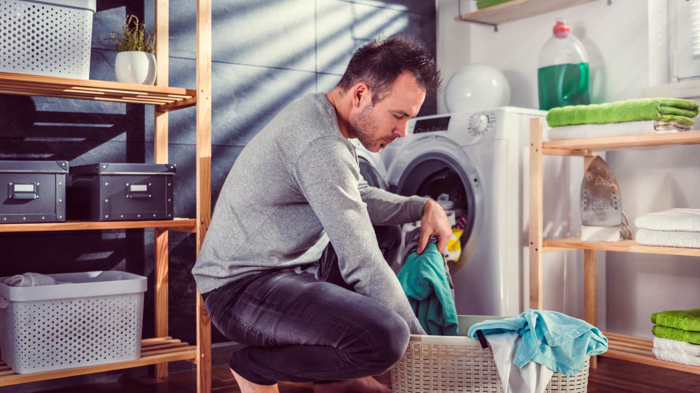 man putting laundry into washing machine