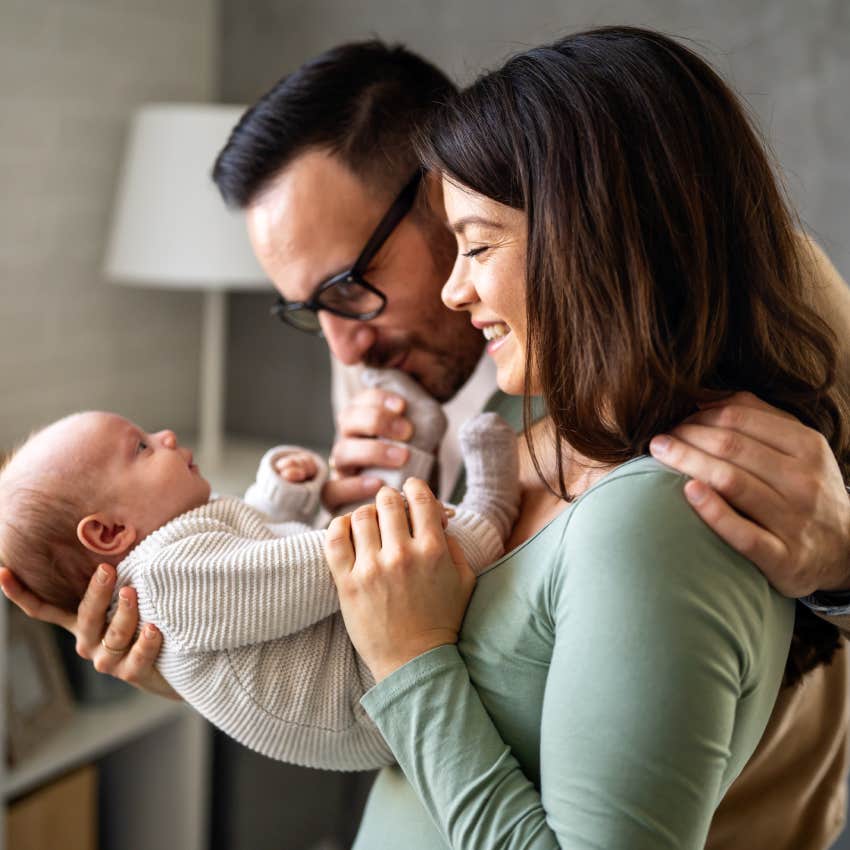 Proud mother and father smiling at their newborn baby daughter