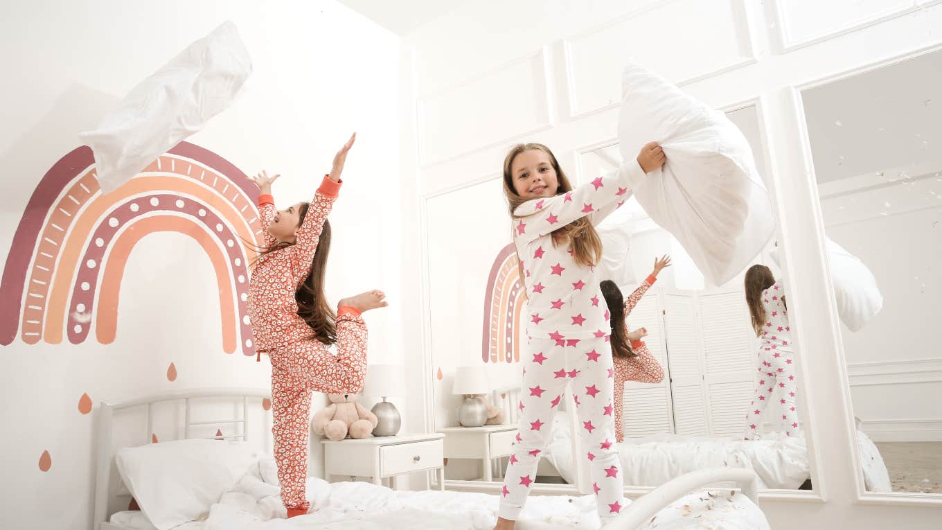 two little girls having pillow fight at sleepover