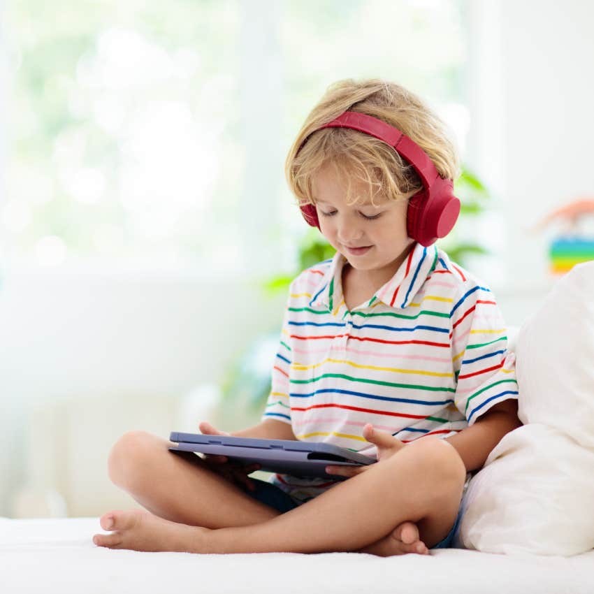 child playing on tablet with headphones on