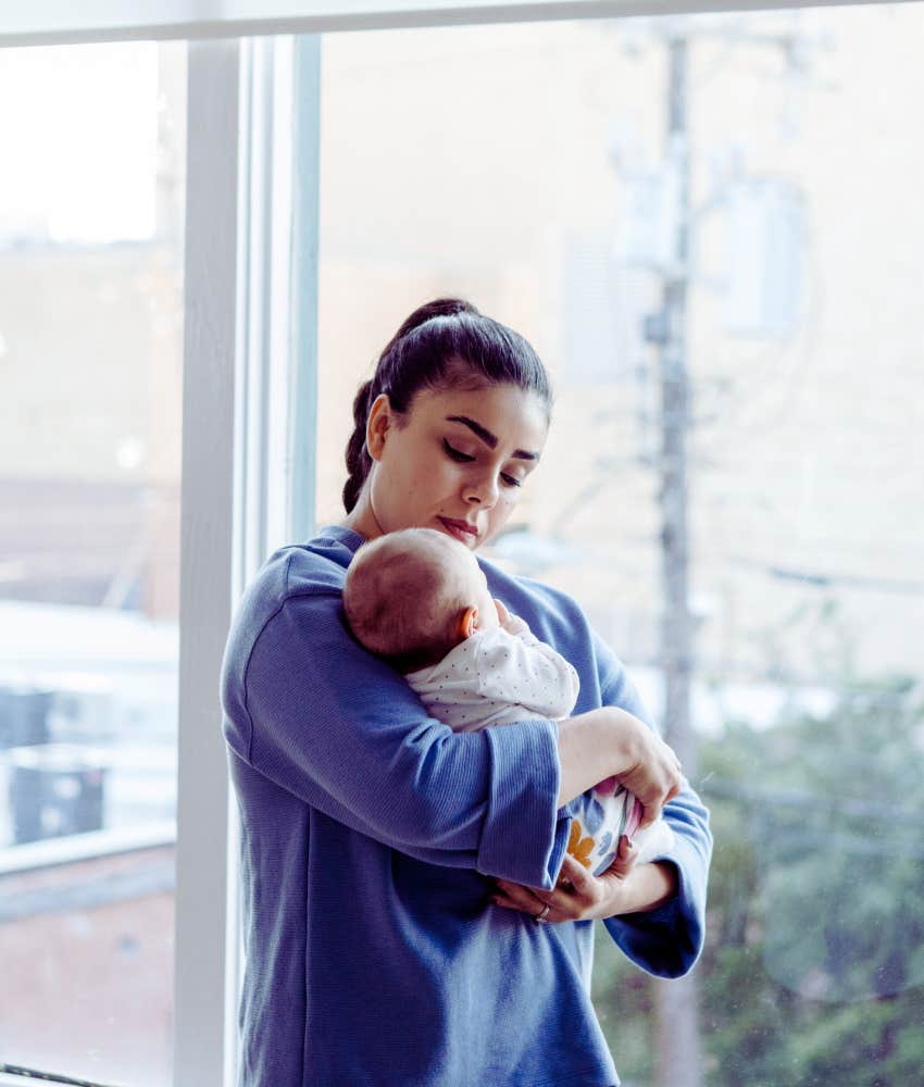 nanny holding baby near window