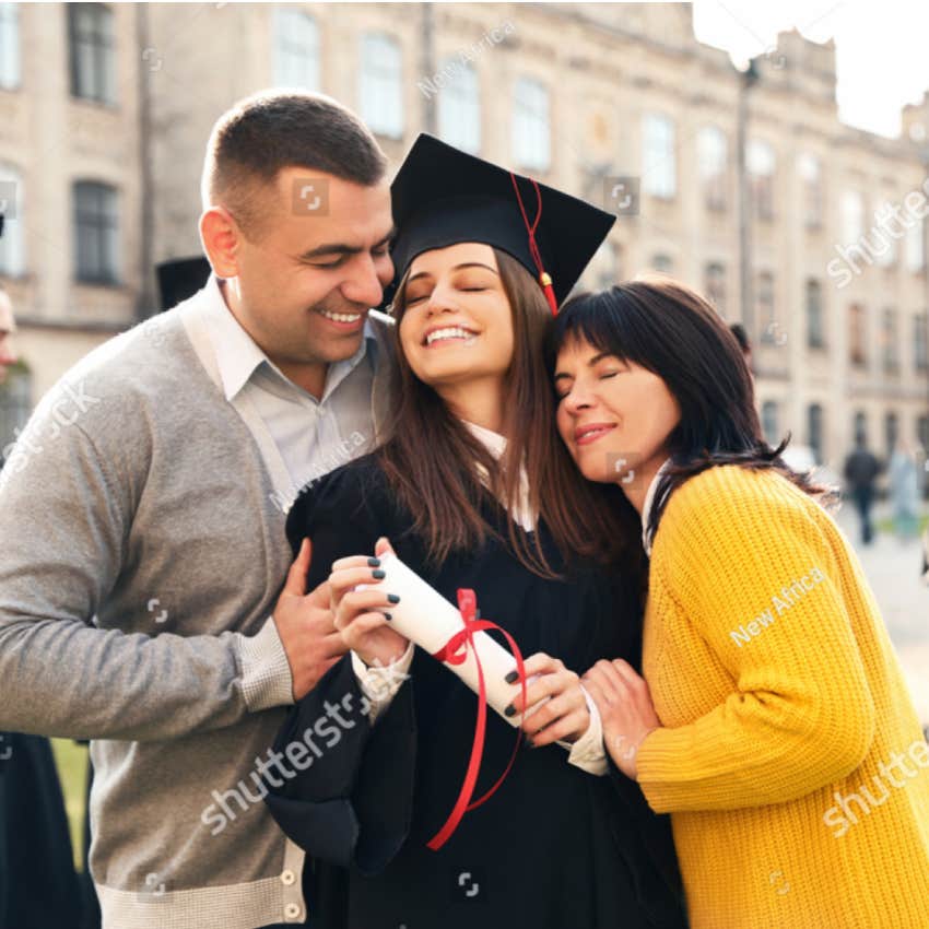 proud parents hug high school graduate
