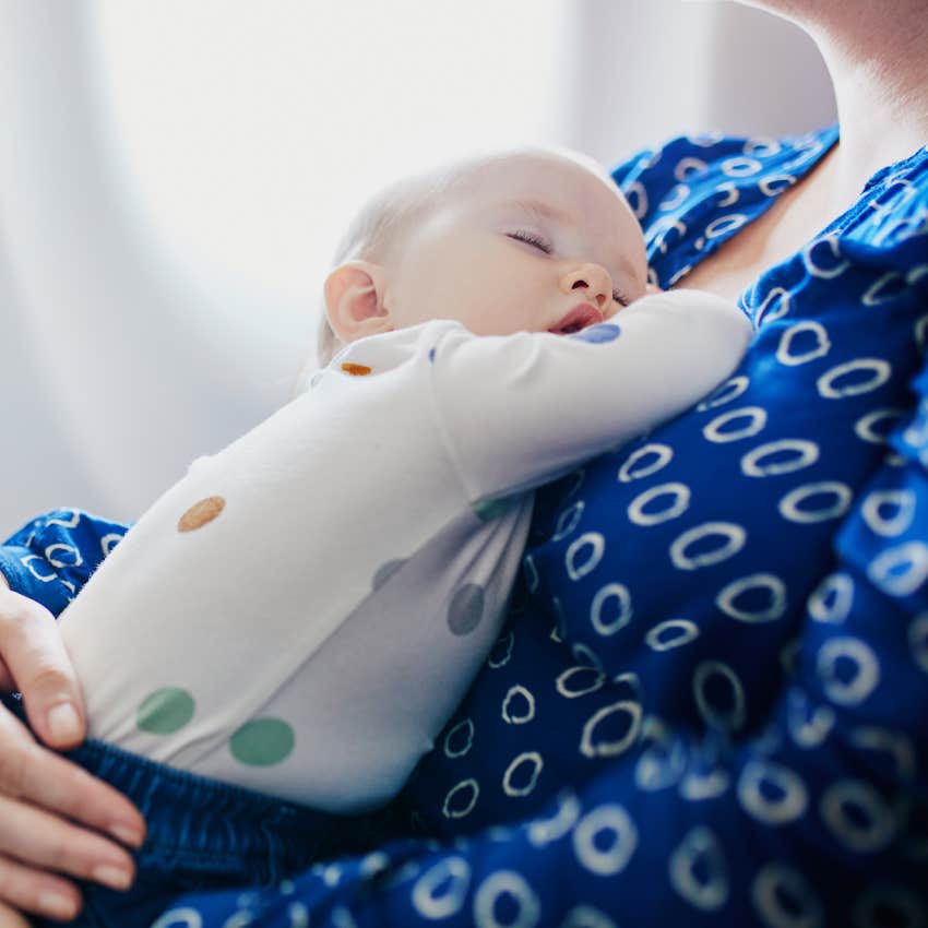 Mother holding her sleeping baby during the flight