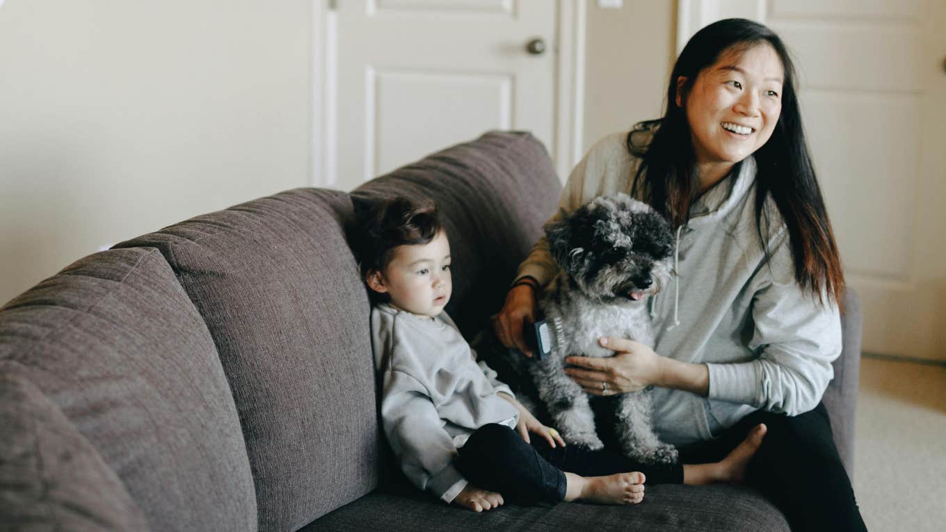 A mom with her dog and toddler on a couch.