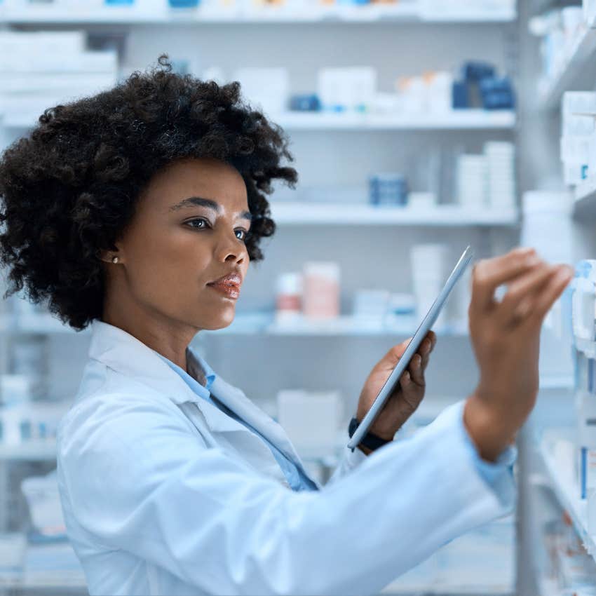 Pharmacist looking at medications on shelf. 